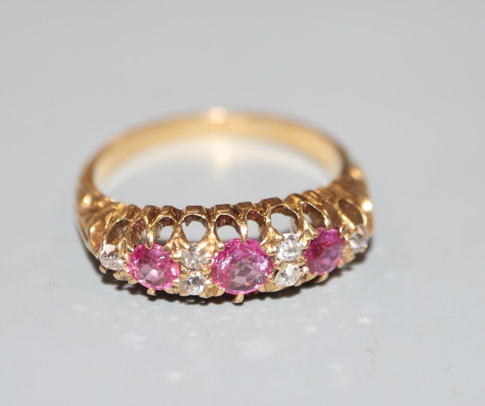 An early 20th century 18ct and graduated three stone ruby and diamond chip set half hoop ring, size M, gross 3.6 grams.